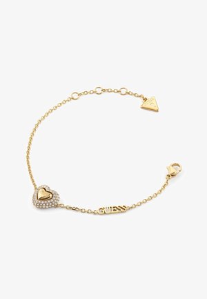 Goldene Kettenarmband mit einem herzförmigen Anhänger mit Strasssteinen und einem Logo, neben einem dreieckigen Tag. Verstellbarer Verschluss für eine optimale Passform.
