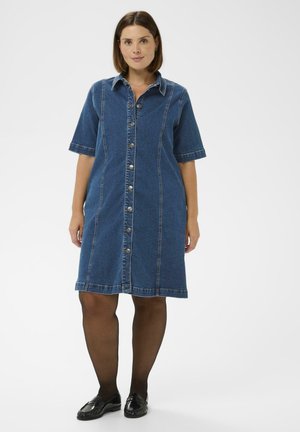 Džínové šaty-košile s límečkem, krátkými rukávy, zapínáním na knoflíky vpředu a kontrastním prošíváním. Tmavě modrá barva s volným střihem.