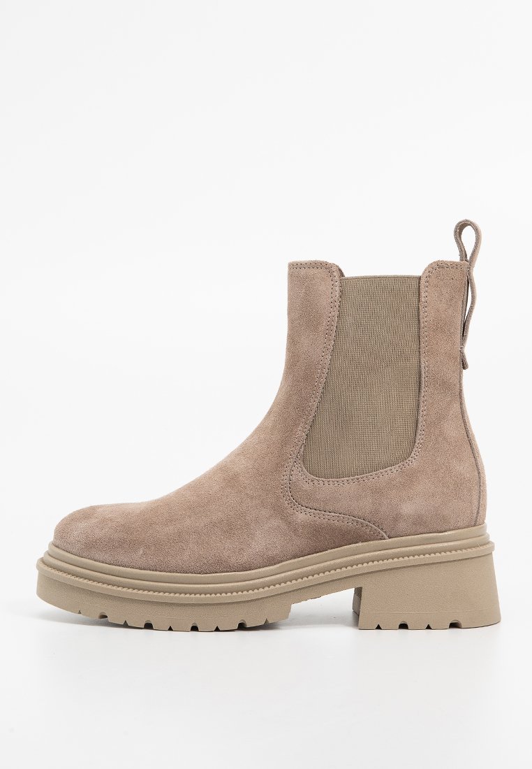 Brązowy zamszowy botek za kostkę z elastycznymi panelami bocznymi, teksturowanym wierzchem, pętlą do zakładania i masywną gumową podeszwą z wyraźnym bieżnikiem.