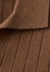 Tessuto a maglia marrone con texture a coste, caratterizzato da un colletto ripiegato. Il materiale appare morbido e leggermente peloso, conferendo calore e confort.