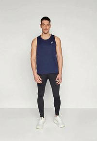 Tumes sinise värvi sleeveless sporditopp, millele on kombinatsiooniks mustad retuusid. Ees on logo ja jalas on valged tossud. Sile kangas, keha lähedane lõige.