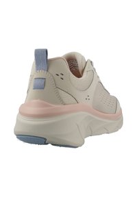 Zapatilla deportiva de color beige claro con una entresuela de suave rosa. Presenta un upper texturizado, un detalle azul en el talón y perforaciones para transpirabilidad.