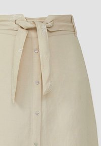 Beige linnen rok met een strik taille, knoopsluiting aan de voorkant en subtiele bloemenborduursels op de tailleband. Gladde textuur, ontspannen pasvorm.