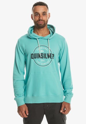 Turquoise cotton hoodie with a front pocket, drawstring hood, and a circular graphic logo that reads "Quiksilver Surf Company."