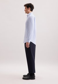 Lichtblauw en wit gestreept overhemd met knopen, lange mouwen, gecombineerd met donkerblauwe broeken en zwarte schoenen, met een getailleerde pasvorm.