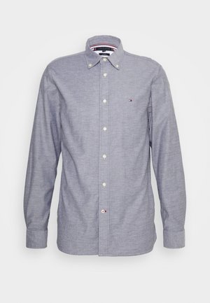 Camisa de manga larga azul claro con cuello abotonado y pequeño logotipo de Tommy Hilfiger en el pecho.