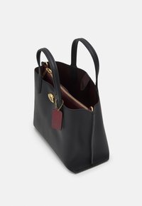 Zwarte leren handtas met een getextureerde afwerking, gouden beslag, een bordeauxrode binnenkant en een bijpassend label. Voorzien van twee bovenhandvatten en een ritssluiting.