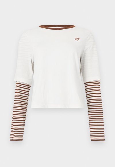 Λευκό κοντό t-shirt με κοντά μανίκια και μακριά μανίκια με καφέ ρίγες. Διαθέτει καφέ γιακά και μικρό λογότυπο «BP» στο στήθος.