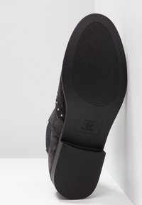 Semelle de botte noire avec bande de roulement texturée et talon bloc, affichant la marque "New Look" et la taille 41/7, photographiée sur fond blanc.