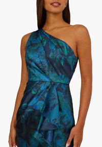 Jednobarevné šaty s jedním ramenem v tmavě modrém saténu s zelenými květinovými vzory, s bočním zavěšením a přiléhavým pasem, hladká textura.