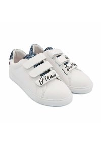 Baskets blanches avec deux bandes Velcro, accents texturés bleu scintillant sur le talon et détails en script noir sur les bandes.