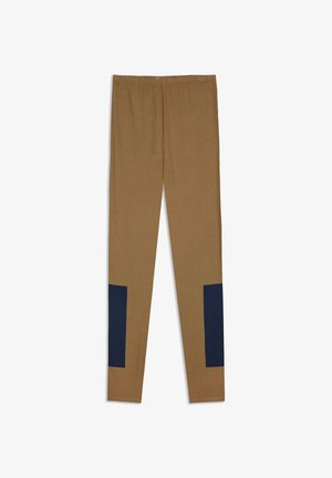 Braune, knöchellange Leggings mit marineblauen rechteckigen Patches an den unteren Außenseiten jedes Beins.