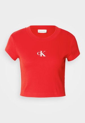 Červené skrátené tričko vyrobené z rebrovaného materiálu, so zaobleným výstrihom a krátkymi rukávmi. Na oblasti hrude je zobrazené biele logo.