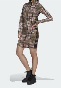 Mekko, jossa on pitkät hihat ja korkea kaula-aukko, esittelee ruutukuosisia maanläheisiä sävyjä, kapea malli ja mustat sivuakkentit. Yhdistetty mustiin korkeisiin tennareihin.