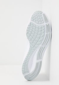 Suola di sneaker bianca con motivo in gomma grigio chiaro. Presenta una presa testurizzata e un design curvo nel tallone, con pendenze lungo i lati.