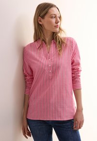 Camicia a maniche lunghe rosa a righe con colletto abbottonato e vestibilità ampia, caratterizzata da strisce verticali bianche e maniche con polsini.