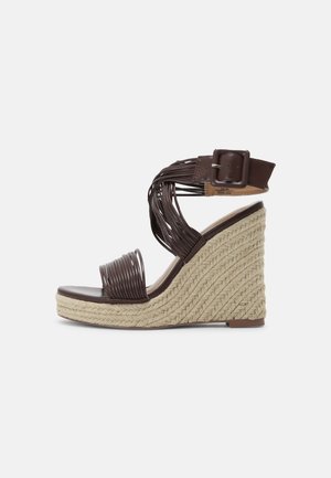 Bruine gevlochten wedge sandalen met een gestructureerde touwzool, open teen en crisscross bandontwerp met een gesp bij de enkel.
