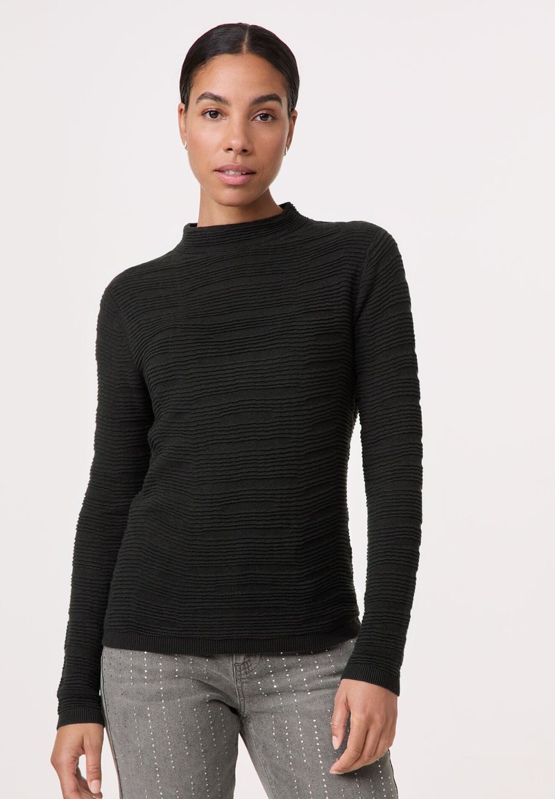 Schwarzer, strukturierter Pullover mit hohem Ausschnitt und langen Ärmeln. Hat ein geripptes Design mit dezenten horizontalen Linien. Kombiniert mit grauen verzierten Jeans.