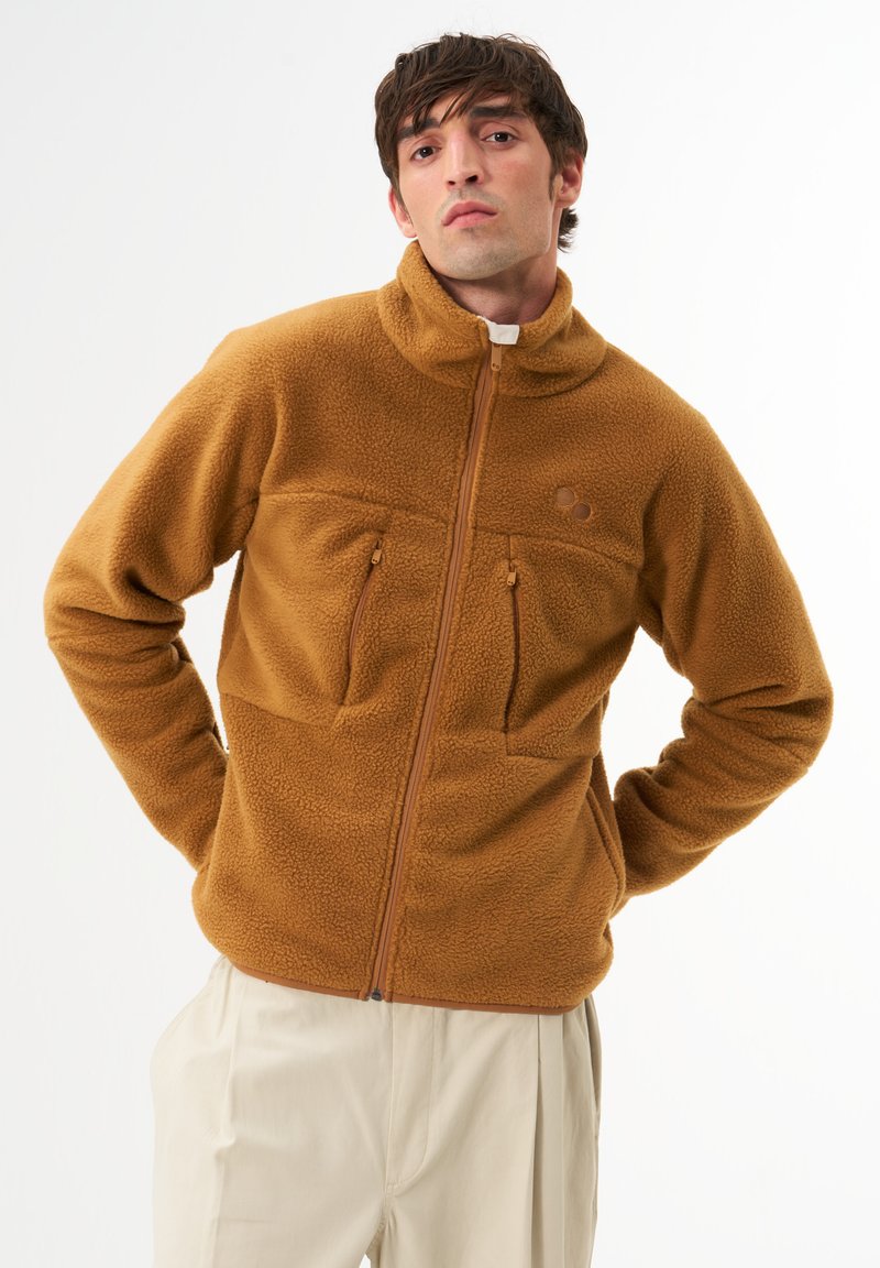 Braune Fleecejacke mit hohem Kragen, Reißverschluss und zwei Brusttaschen. Verfügt über eine strukturierte Oberfläche und Kontrastnähte.