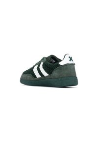 Zapatilla verde con un upper texturizado, rayas blancas y una suela de goma. Presenta un cuello acolchado y un acento blanco en el talón que contrasta.