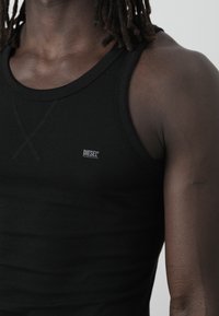 Black cotton tank top with a round neckline, featuring a small white "DIESEL" logo, smooth texture, and fitted design.