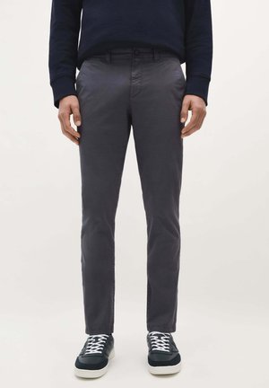 Chinos gris foncé en coton avec une coupe slim, présentant des poches latérales, une fermeture à bouton et portés avec des baskets noires.