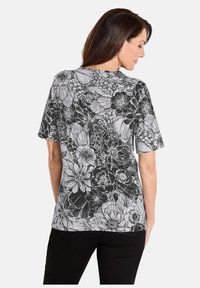 Korte mouw T-shirt in zwart en wit, met een bloemmotief van verschillende bloemen, gemaakt van zachte stof, met een ontspannen pasvorm.
