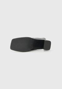 Svart hælboot med jevn overflate, firkantet tåform og tykk, firkantet hæl. Sålen er flat og solid, designet for stabilitet.