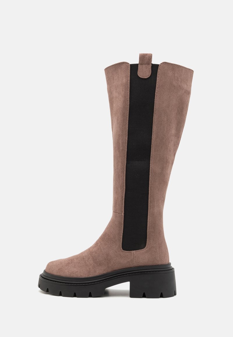 Botă până la genunchi din suede taupe deschis, cu panouri elastice laterale negre, vârf rotund și talpă chunky neagră cu un profil adânc pentru aderență.
