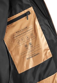 Svart och guldfärgad insida på jackficka med dragkedja, med "Polo Club"-märke och ikoner för ultralätt, skräddarsydd passform, varm, vattenavvisande, återvunnen polyester.