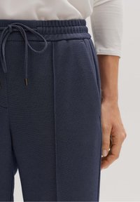 Marinblå strukturerade joggbyxor med elastisk midja och dragsko. Har sidofickor och en slim fit-design.