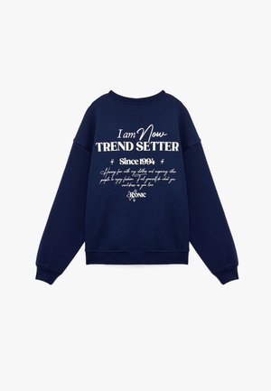 Sudadera azul marino de mezcla de algodón, con el texto blanco "Soy el MARCADOR DE TENDENCIAS Desde 1994" acompañado de elementos decorativos y un cuello redondo.