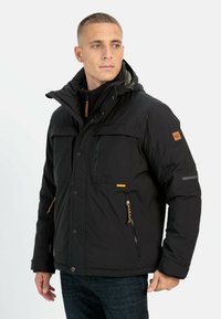 Black insulated jacket with a hood, featuring zippered pockets, a snap front, and accents of yellow and brown leather. Textured fabric.