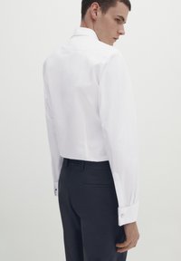 Witte button-up shirt met een klassieke kraag, lange mouwen en dubbele manchetten. Draagt men met donkere broeken, die een op maat gemaakte pasvorm en een gladde textuur laten zien.