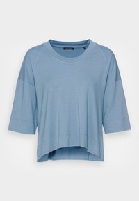 Maglietta azzurro chiaro a maniche corte con una vestibilità rilassata. Presenta un collo rotondo, maniche raglan e un orlo leggermente curvo. Tessuto morbido.