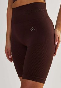 Hnědé žebrované cyklistické šortky s vysokým pasem. Mají malé logo srdce na kapse. Vyrobeny z elastického materiálu pro pohodlí a dobré padnutí.
