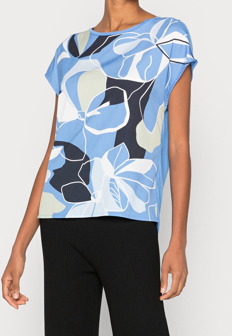 Krátký rukáv modrý top s květinovým vzorem v bílé, námořnické a světle zelené, vyrobený z měkké tkaniny s uvolněným střihem.