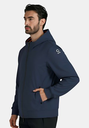 Giacca blu navy con cappuccio, chiusura con zip e tasche laterali. Presenta una fodera interna rosso-arancio e un dettaglio del logo sulla manica.
