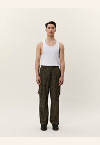 Top alb, pantaloni cargo oliv cu un model texturat și încălțăminte neagră. Vedere frontală directă pe un fundal neutru.