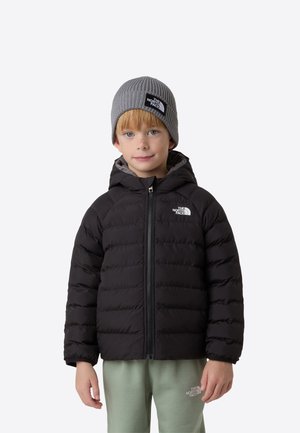 Chaqueta de plumas negra con capucha, con un diseño acolchado y cremallera frontal. Combinada con un gorro gris de canalé. Pantalones verde claro visibles.