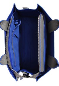 Sac en toile bleu avec un intérieur lisse, doté d'une fermeture éclair grise et de poches, de poignées robustes et d'une base plate pour la stabilité.