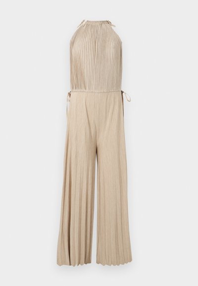 Combinaison beige plissée sans manches avec col halter et pantalon large, avec liens latéraux à la taille.