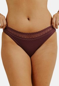 Bas de bikini bordeaux à taille basse, avec une bordure en dentelle texturée le long de la taille et un tissu lisse.