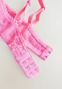 Pink lace bra with sheer panels, adjustable straps, and hook-and-eye closure. Features floral lace trim along the edges. Soft texture.