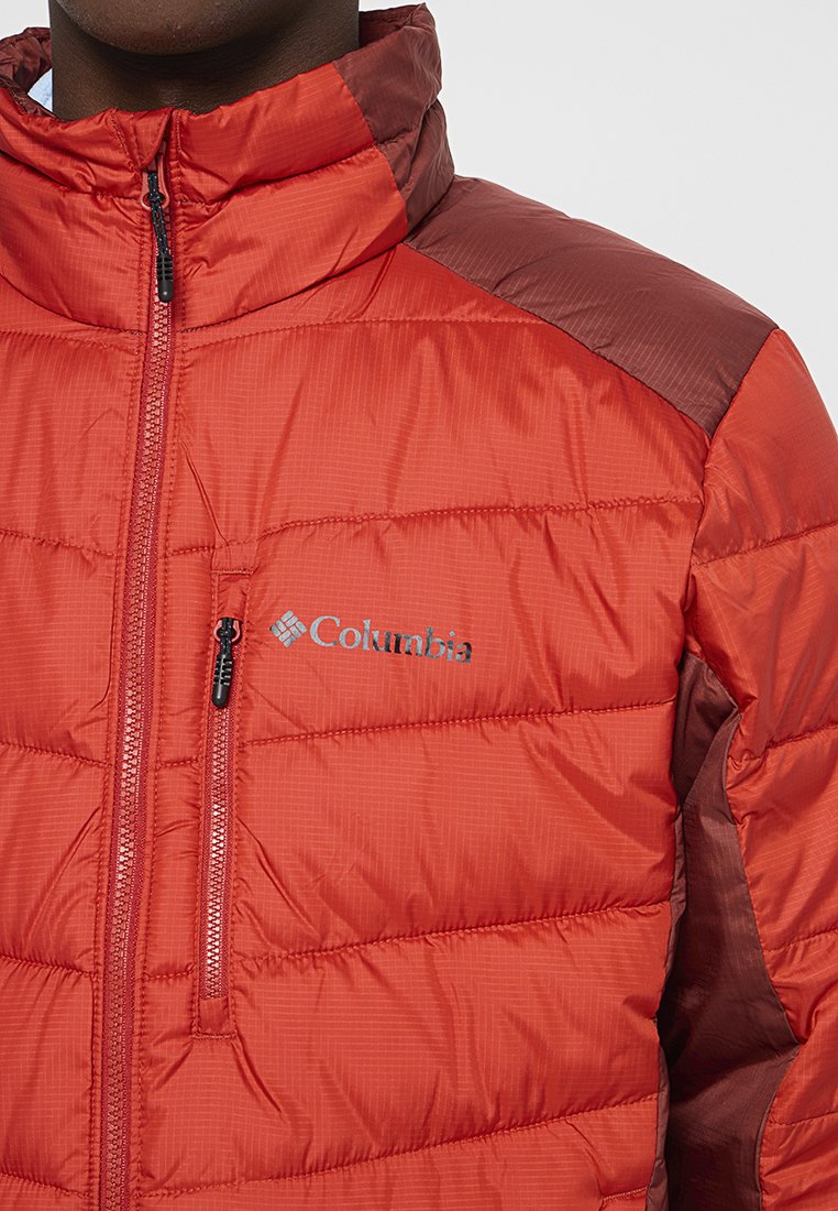 Czerwona kurtka puchowa z pikowanym wzorem. Posiada wysoki kołnierz i zamek błyskawiczny z przodu oraz ciemniejszy czerwony akcent na ramionach i logo.