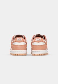 Nike-sneakers med ett överdel i rosa mocka och vita detaljer, rundad form, vadderad krage och en texturerad gummisula.