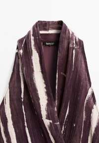 Col de kimono en tissu côtelé rayé violet et blanc avec étiquette Massimo Dutti, fabriqué au Portugal, présenté sur un fond blanc.