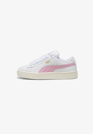 Zapatilla baja blanca de Puma con franja rosa, logo dorado, collar acolchado y suela de goma texturizada de color blanco roto, mostrada de perfil.