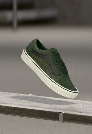 Green suede sneakers with a black leather side stripe, lace-up design, white midsole, and rubber outsole, showcasing a smooth texture.