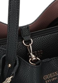 Geantă de mână din piele texturată neagră, cu accesorii aurii, având un închizător cu fermoar și un interior într-o nuanță contrastantă de mov.